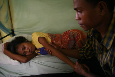 A man comforts a woman with malaria